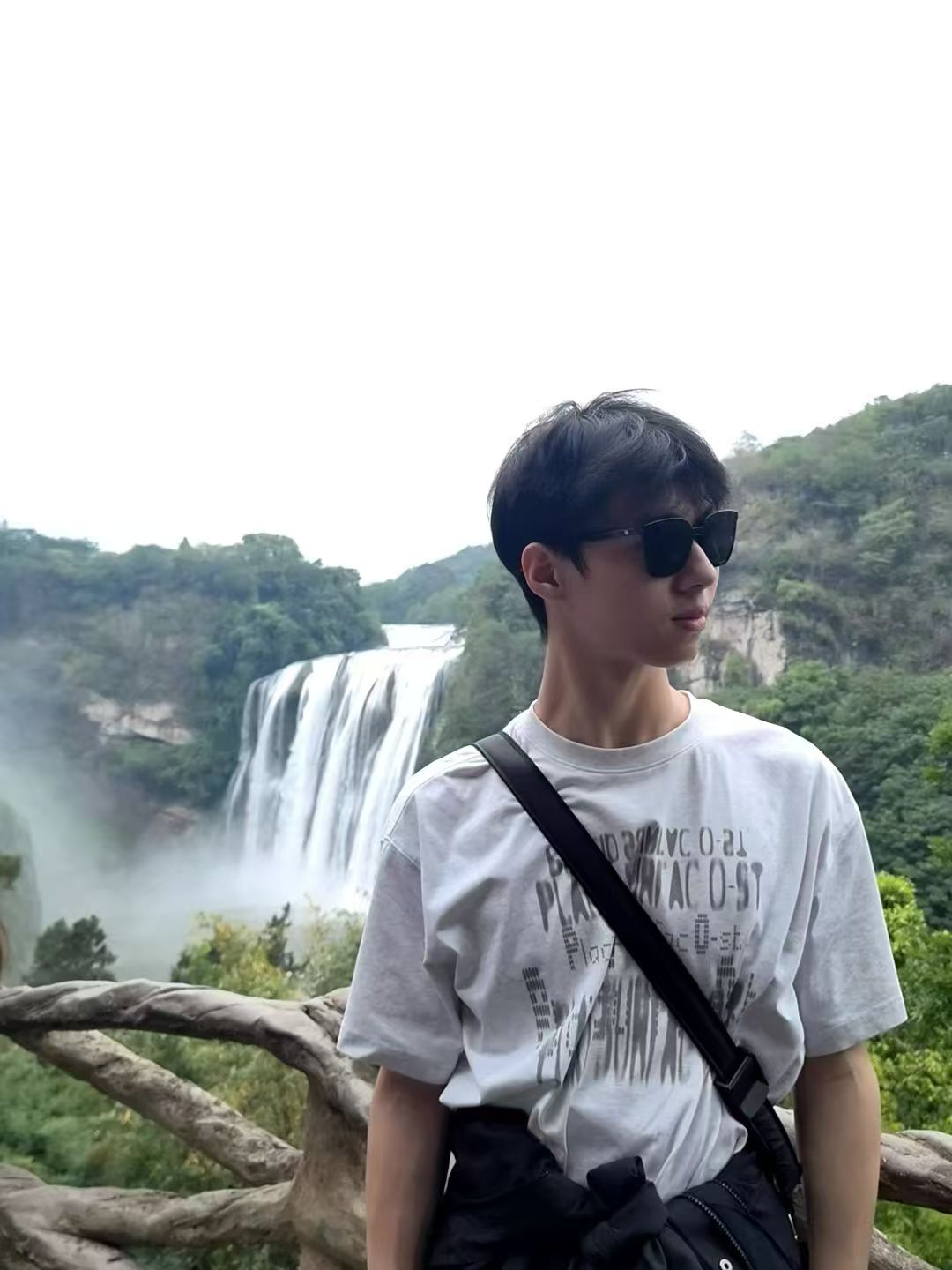 Mengbing Zhou standing in front of a waterfall